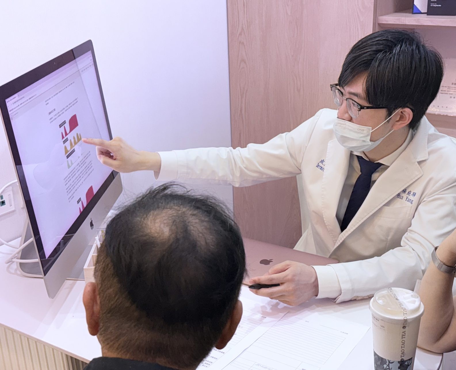 楊庭驊醫師在診間看資料並與患者說明評估內容